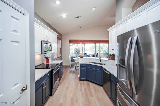 kitchen with blue cabinetry, vaulted ceiling, sink, white cabinets, and appliances with stainless steel finishes