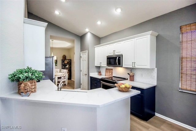 kitchen with lofted ceiling, kitchen peninsula, white cabinetry, appliances with stainless steel finishes, and light hardwood / wood-style floors