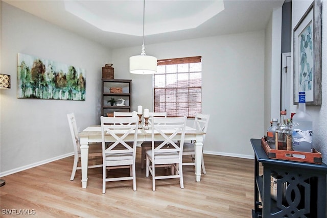 dining area with a raised ceiling and hardwood / wood-style floors