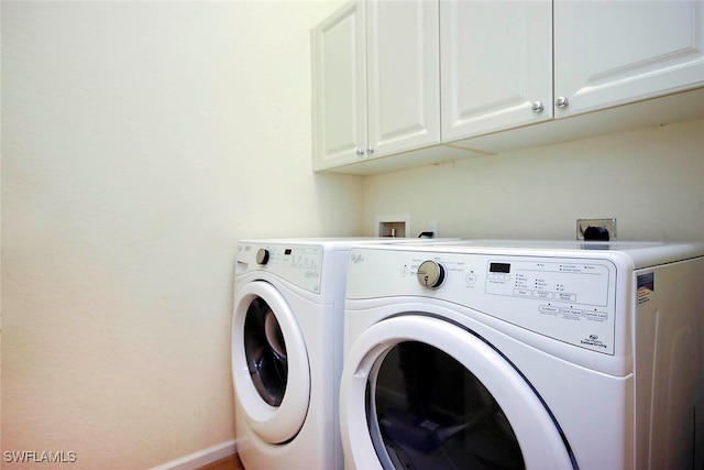 clothes washing area with washer and dryer and cabinets