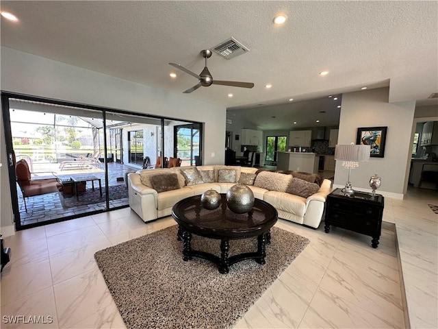 living room featuring ceiling fan and a textured ceiling