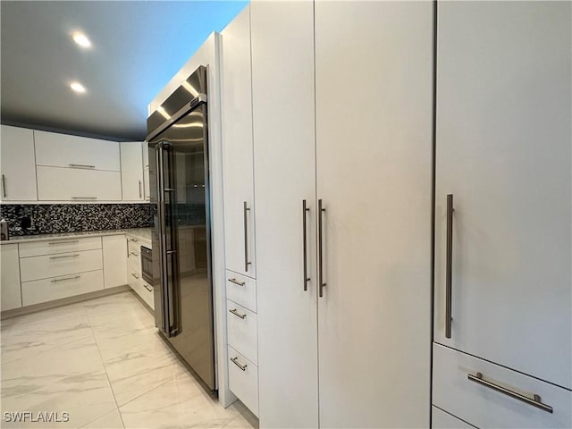 kitchen with white cabinets, high end refrigerator, and tasteful backsplash