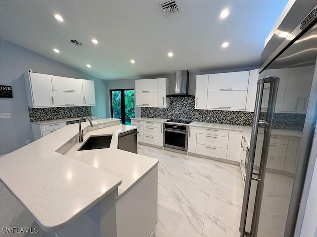 kitchen featuring a spacious island, sink, appliances with stainless steel finishes, white cabinets, and wall chimney exhaust hood