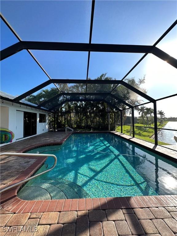 view of swimming pool featuring a lanai, a water view, and a patio