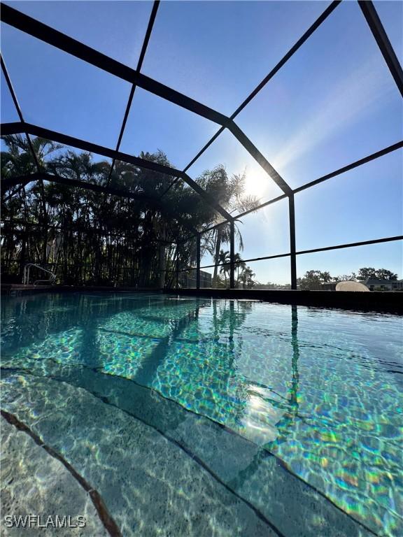 view of swimming pool featuring a lanai and a water view