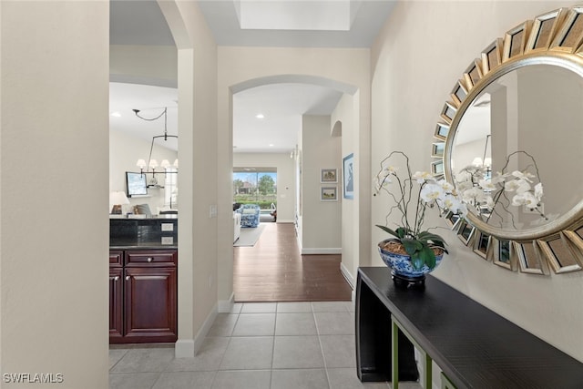 hallway with a chandelier and light tile patterned floors