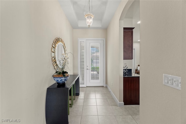 tiled entrance foyer with a tray ceiling