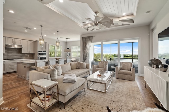 living room featuring dark wood-type flooring, a raised ceiling, and ornamental molding