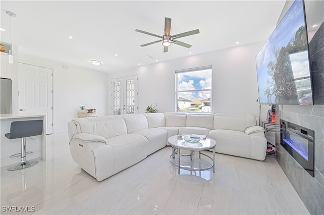 living room featuring ceiling fan and a tile fireplace