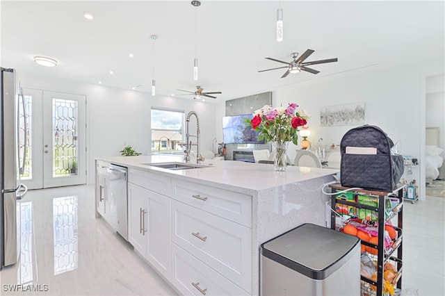 kitchen featuring white cabinets, pendant lighting, sink, a kitchen island with sink, and appliances with stainless steel finishes