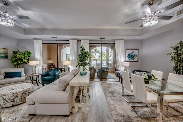 living room with ceiling fan, a raised ceiling, and light hardwood / wood-style floors