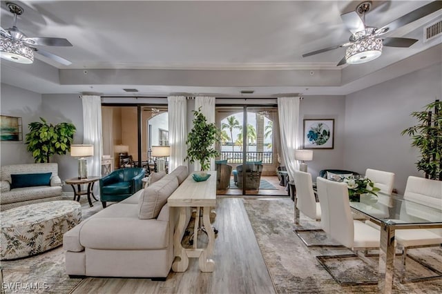 living room featuring a tray ceiling, ceiling fan, and light hardwood / wood-style flooring