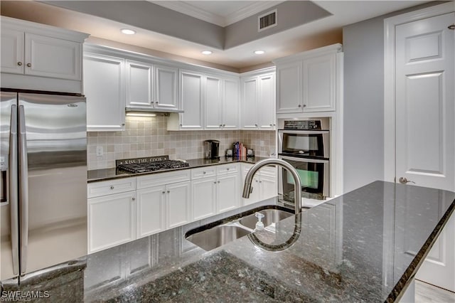 kitchen featuring stainless steel appliances, dark stone counters, white cabinets, and sink