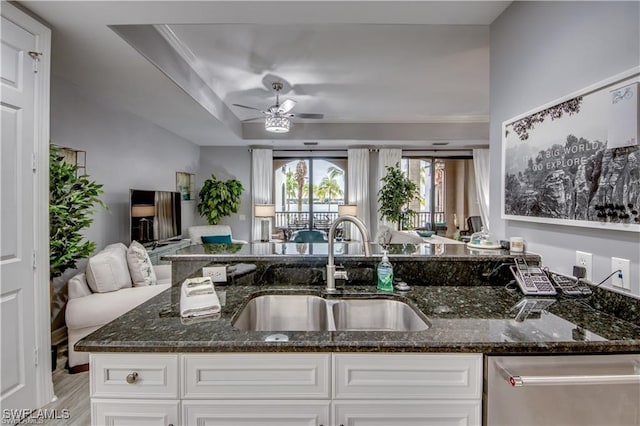 kitchen with sink, ceiling fan, white cabinetry, stainless steel dishwasher, and dark stone counters