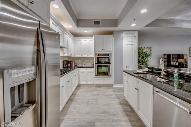 kitchen featuring appliances with stainless steel finishes, dark stone counters, white cabinetry, and sink