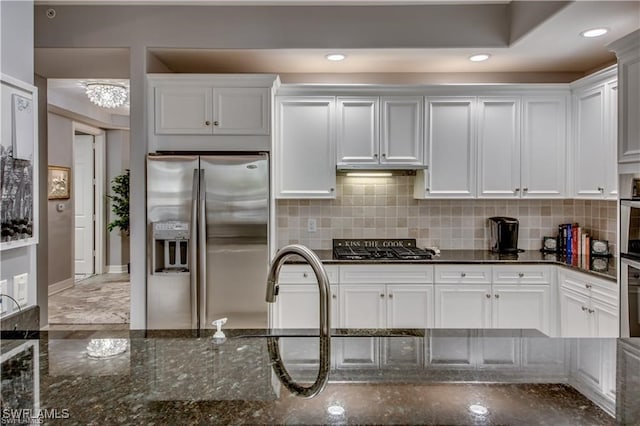 kitchen with dark stone countertops, stainless steel refrigerator with ice dispenser, and white cabinetry