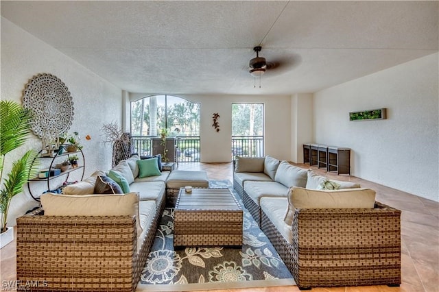 living room featuring ceiling fan, a textured ceiling, and light tile patterned flooring