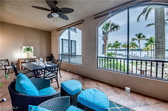 sunroom / solarium with a water view, plenty of natural light, and ceiling fan