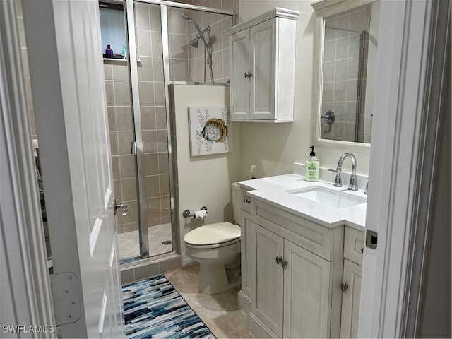 bathroom with tile patterned floors, a shower with shower door, vanity, and toilet