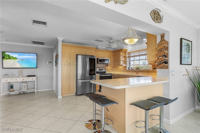 kitchen with light brown cabinetry, appliances with stainless steel finishes, light tile patterned flooring, kitchen peninsula, and a kitchen breakfast bar