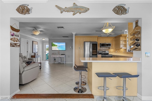 kitchen featuring a kitchen breakfast bar, kitchen peninsula, ornamental molding, appliances with stainless steel finishes, and tasteful backsplash