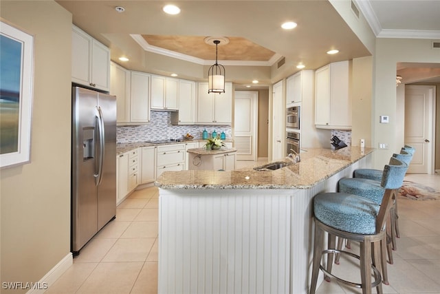 kitchen featuring stainless steel appliances, a raised ceiling, kitchen peninsula, pendant lighting, and a kitchen breakfast bar