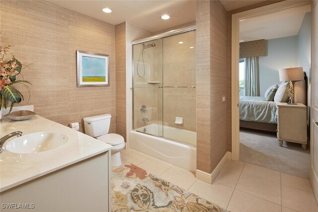 full bathroom featuring shower / bath combination with glass door, vanity, tile patterned flooring, and toilet