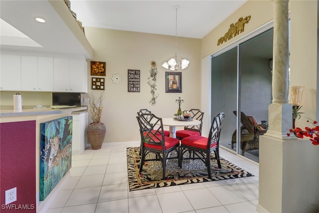 dining area with decorative columns, a notable chandelier, and light tile patterned floors