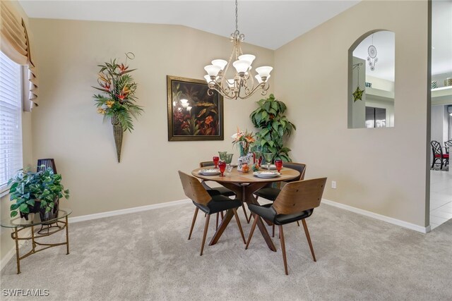 dining space featuring light carpet, an inviting chandelier, and vaulted ceiling