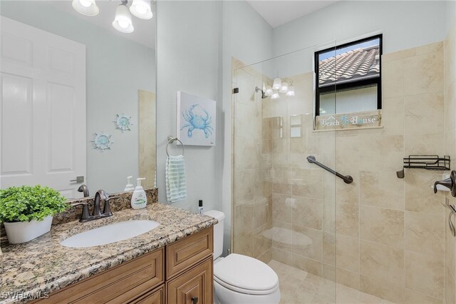 bathroom with vanity, toilet, and tiled shower