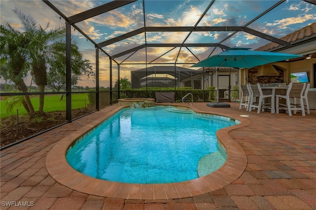 pool at dusk featuring a patio area and a lanai