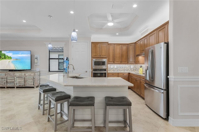 kitchen featuring sink, a kitchen island with sink, stainless steel appliances, and a raised ceiling