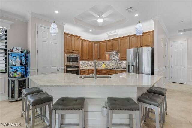 kitchen with a large island with sink, sink, a kitchen bar, hanging light fixtures, and stainless steel appliances