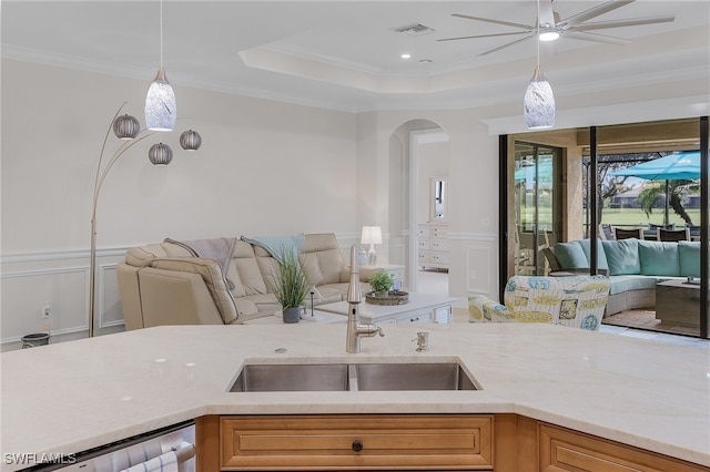 kitchen with ceiling fan, ornamental molding, sink, and hanging light fixtures