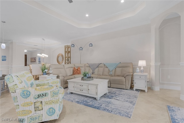 tiled living room featuring ornamental molding, decorative columns, a tray ceiling, and an inviting chandelier