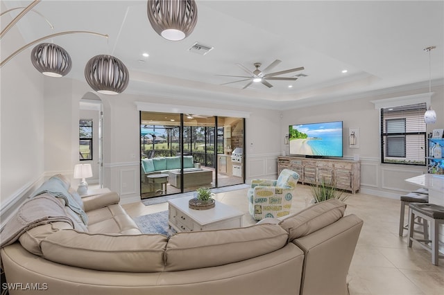 living room with ornamental molding, a tray ceiling, and ceiling fan