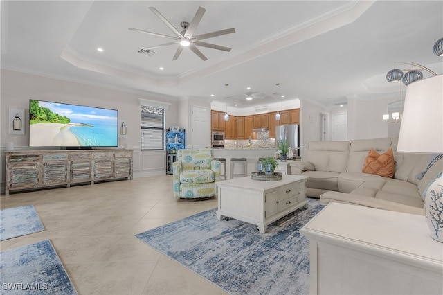 living room with crown molding, ceiling fan with notable chandelier, and a raised ceiling