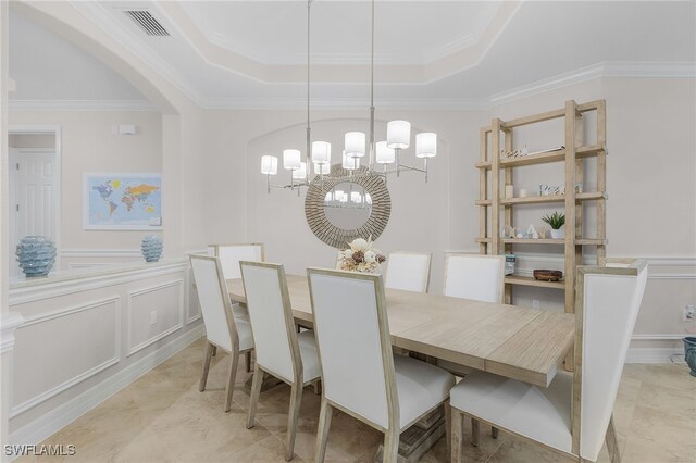 dining area with crown molding, an inviting chandelier, and a raised ceiling