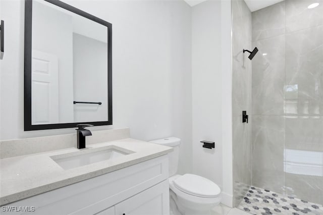 bathroom featuring vanity, tile patterned floors, toilet, and tiled shower