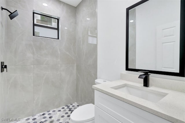 bathroom featuring vanity, tiled shower, and toilet