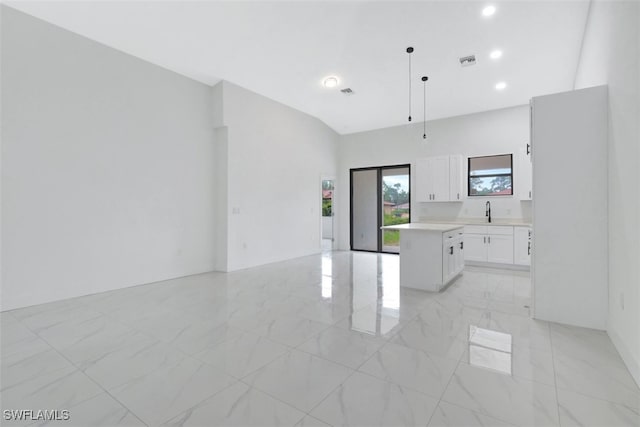 kitchen with pendant lighting, sink, white cabinetry, and a center island