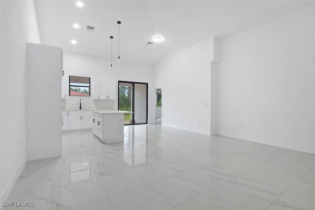 kitchen with pendant lighting, white cabinets, a kitchen island, and sink