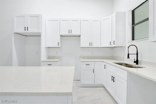 kitchen featuring light stone countertops, sink, and white cabinets