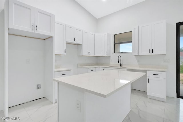 kitchen with white cabinets, a kitchen island, and sink