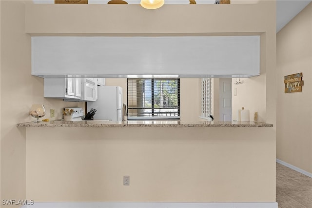 kitchen featuring white appliances, light stone countertops, white cabinetry, and kitchen peninsula