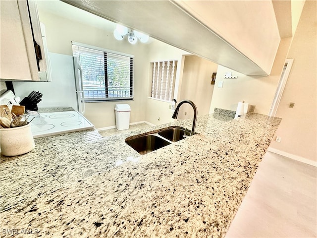 kitchen with light stone countertops, sink, and kitchen peninsula