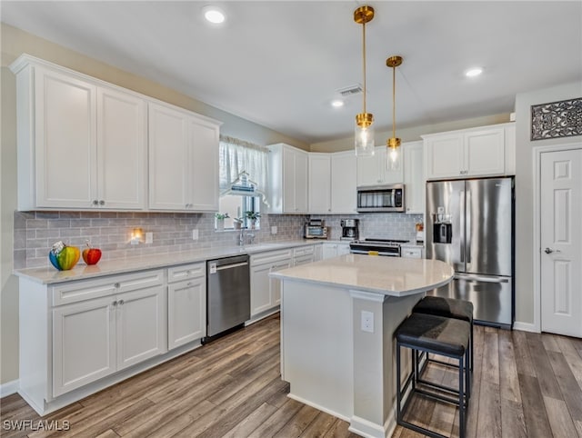 kitchen with stainless steel appliances, a kitchen island, light wood-type flooring, and white cabinetry