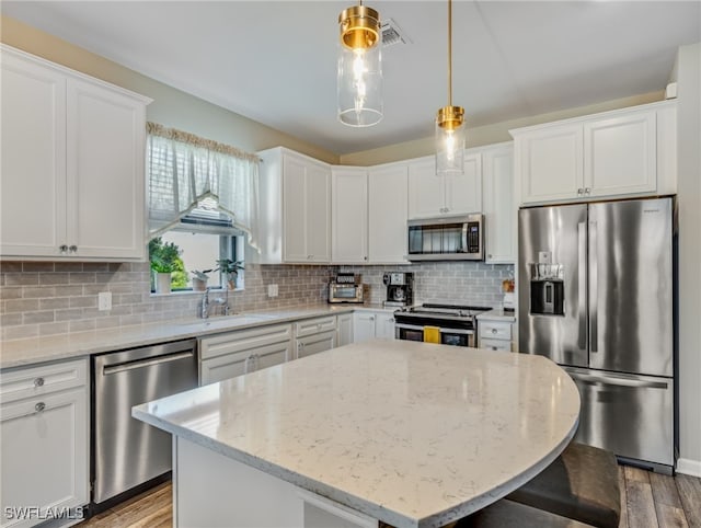 kitchen featuring light stone counters, white cabinets, appliances with stainless steel finishes, and a center island