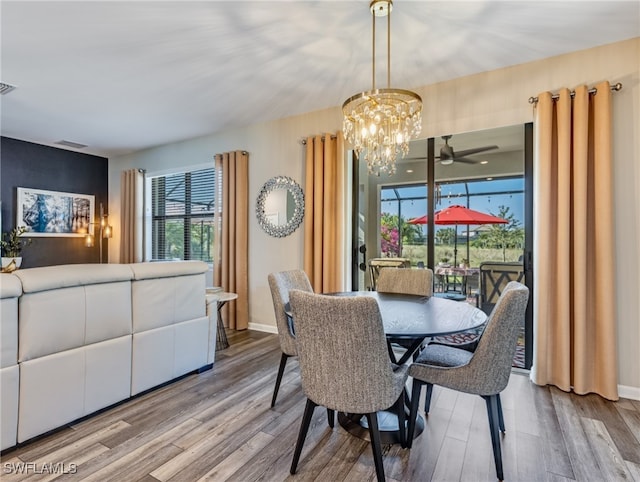 dining room featuring ceiling fan with notable chandelier, light wood-type flooring, and a healthy amount of sunlight