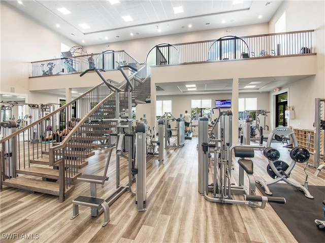 exercise room featuring light hardwood / wood-style floors and a high ceiling